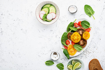 Fresh vegetables for cooking. Colored tomatoes, fresh cucumbers, radish, spinach for a light snack or garnish to the main course. Top View.