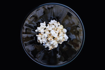 Popcorn in a black bowl with reflection. Black background