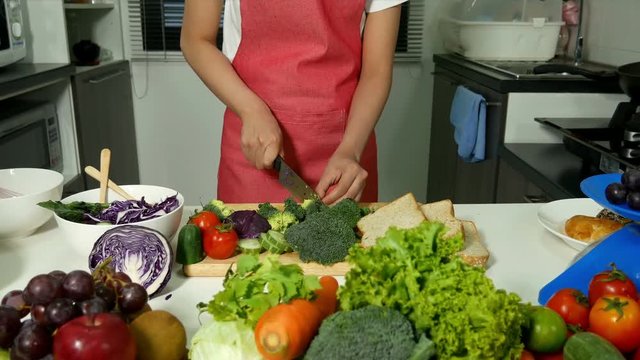 4k of happy woman cutting green fresh broccoli in kitchen room at home