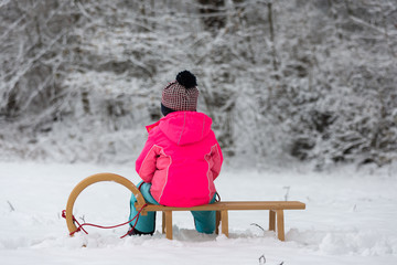 A child sits on a sledge in a snow-covered landscape