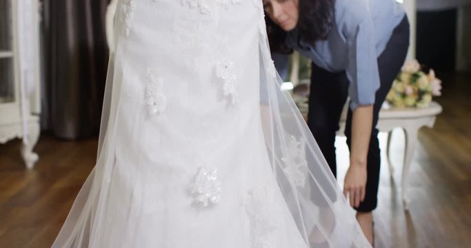 4k, Woman adjusting wedding dress on a mannequin in her shop. Slow motion.