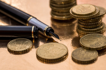 euro coin and pen isolated on gold