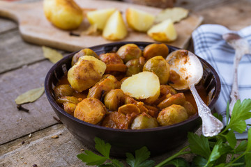 Roasted fresh brussels sprouts with potatoes in homemade ceramic bowl.