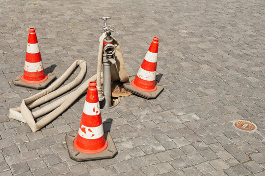 Pilonen sichern einen Unterflur-Hydrant mit einem montierten Standrohr f&uuml;r Bauwasser