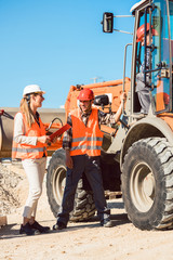 Bauingenieur und Arbeiter diskutieren auf Straßenbau Baustelle, Frau und Mann