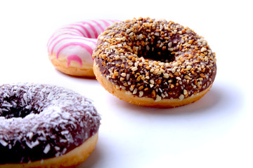 Assorted doughnuts in the glaze, colorful sprinkles and nuts on a white background.