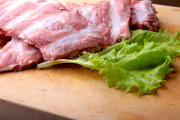 Raw Ribs on a rustic cutting board with salt, pepper and grinder for spices . copy space. Top View.