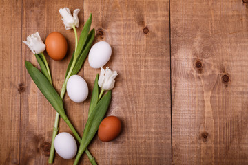 Tulips flowers and eggs decoration on wooden background. Top view, text space