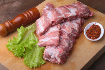 Raw Ribs on a rustic cutting board with salt, pepper and grinder for spices . copy space. Top View.