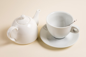 Fototapeta na wymiar White teapot and an empty cup of tea spoon.