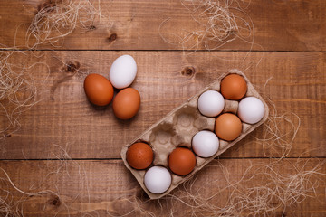 Eggs in pack on wooden table. Top view, text space