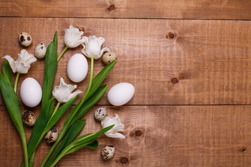 Tulips flowers and eggs decoration over wooden background. Top view, text space