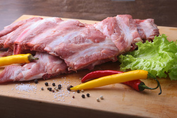 Raw Ribs on a rustic cutting board with salt, pepper and grinder for spices . copy space. Top View.