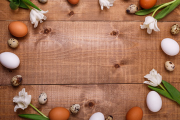 Tulips flowers and eggs decoration over wooden background. Top view, text space