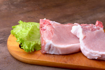 Raw chop on a rustic cutting board with salt, pepper and grinder for spices . for copy space. Top View.