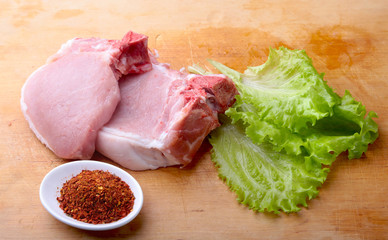 Raw chop on a rustic cutting board with salt, pepper and grinder for spices . for copy space. Top View.