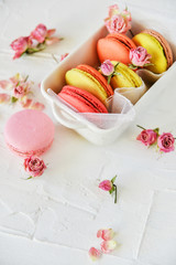 Delicate Fresh Colorful French Macaroons In Pastel Colors With Flowers Roses On A Light Textile Background, Top View