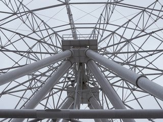 Closeup of a Ferris wheel at an amusement park on a cloudy sky.