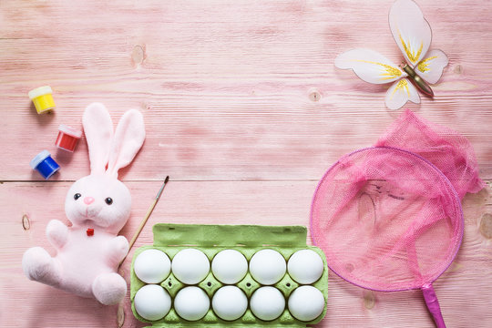 Easter festive set with eggs, flower and easter rabbit, paint, brush, butterfly, net on rustic wooden table with copyspace. Flat lay, space for mock up and copy space. Top view.