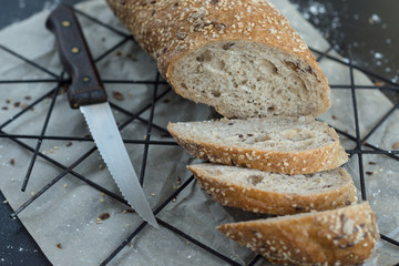 Baguette on a black background. Baguette with seeds and sesame.Baguette with knife. Sliced ​​baguette on the table.