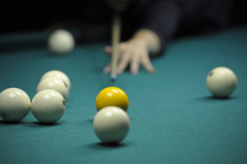 Billiard: a pool player gets ready to stroke a ball with a cue