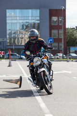 L-driver motorcyclist doing exercise with cones on asphalt ground