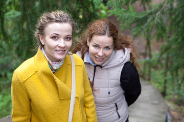 Two smiling young women standing together and looking at camera