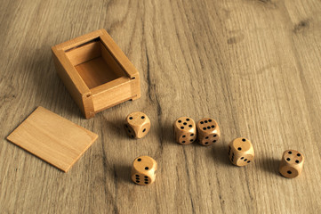 Wooden round corner dice six sided dots set for playing with box on wooden board surface as background
