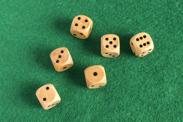 Wooden round corner dice six sided dots set for playing on dark green poker table felt cloth surface as background