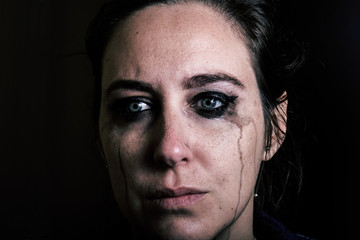 Girl crying with light eyes with blurred makeup. Violence against woman