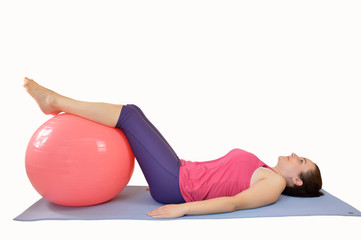 Fototapeta premium Shot of an attractive young woman working out with an exercise ball against a white background