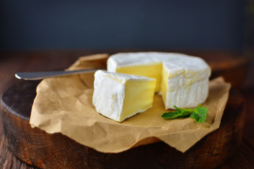 Tasty camembert cheese cut on an old oak cooker in a home rustic kitchen.