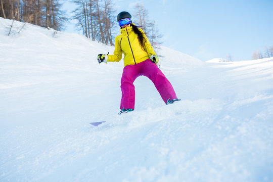 Image of sports woman in helmet and snowboarding mask from snowy slope with trees