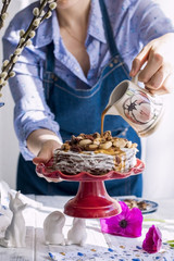 A woman and a cake of thin pancakes with white cream and nuts. Milkman with flowers in the hands of the girl. Spring fresh flowers. Breakfast in the morning. Card.