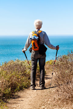 Active Senior Man Hiking On A Trail Stops To Look At A View Of The Ocean. Location: Northern California, Muir Beach. View Of Man From The Back. Copy Space.