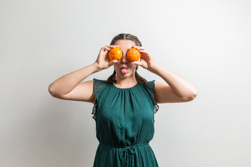 Cute girl shows tongue while holding oranges like eyes