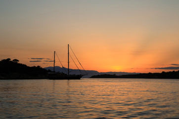 Beautiful sunset sailboat anchoring in a bay near Porto Heli, Peloponnese, Greece.