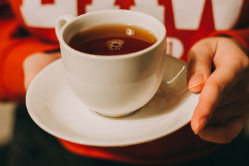 Close-up of a woman's hand holding a cup of hot tea