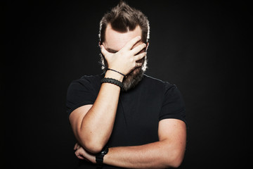 The man put his hand to his face in Studio on a black background. He's very unhappy and sad. Body...