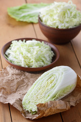 Cabbage, shredded cabbage in a clay bowl on a wooden background, home cooking, vegetarian, fresh vegetables, rustic style, Chinese cabbage on parchment paper, minimalism