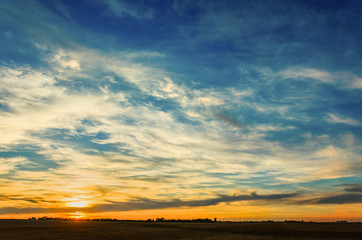 A juicy orange sunset with a huge blue sky and white clouds