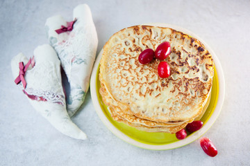 Pancakes with frozen berries pile in a green plate  on a light gray background