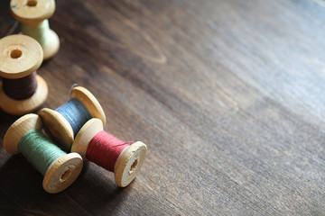 Sewing thread on a wooden background. Set of threads on bobbins 