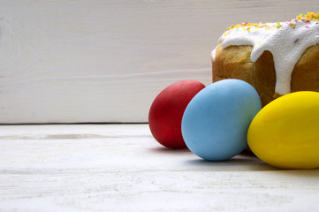 Easter cake and easter colored eggs on white wooden background