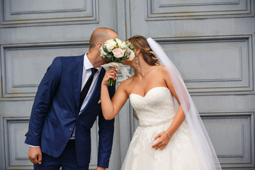 Wedding day. Newlyweds couple kissing and closing with a wedding bouquet. Happy marriage concept