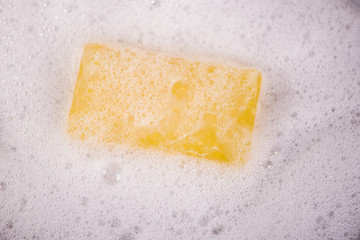yellow lemon glycerine soap in bubbles with fresh slices of lemon and orange