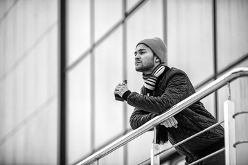 Vape man. Portrait of a handsome young white guy in casual clothes vaping an electronic cigarette opposite the futuristic modern building. Lifestyle.