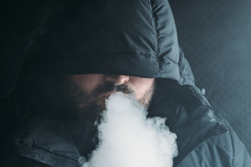 Man vaping e-cigarette with e-liquid. Vape concept