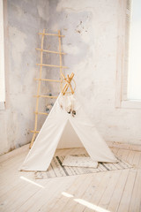 Childen's room corner with a beautifully decorated play tipi tent and a round grey carpet