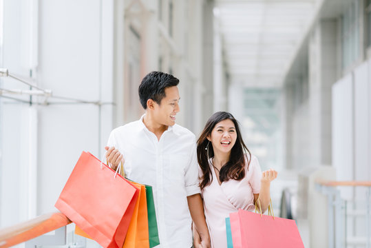 Happy Asian couple enjoy shopping in mall